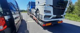 Od lewej: oznakowany furgon mazowieckiej Inspekcji Transportu Drogowego i przejeżdżający przez inspekcyjne wagi ciągnik siodłowy z naczepą niskopodwoziową. Nienormatywny zestaw przewozi dwa samochody ciężarowe.