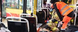 Osoba poszkodowana leżąca na podłodze w tramwaju. Obok strażak i ratownik medyczny.