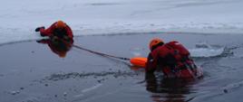 Strażak za pomocą rzutki wyciąga osobę pod którą załamał się lód