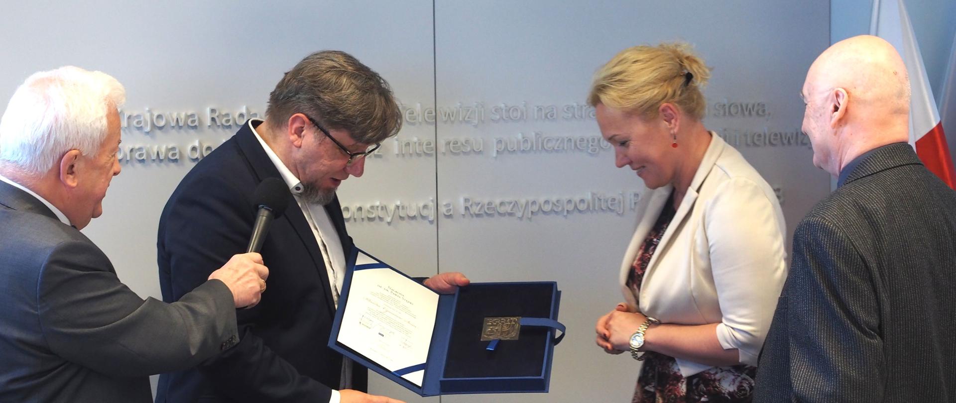 Zdjęcie w poziomie. Przewodniczący KRRiT Witold Kołodziejski wręcza dyplom laureatce