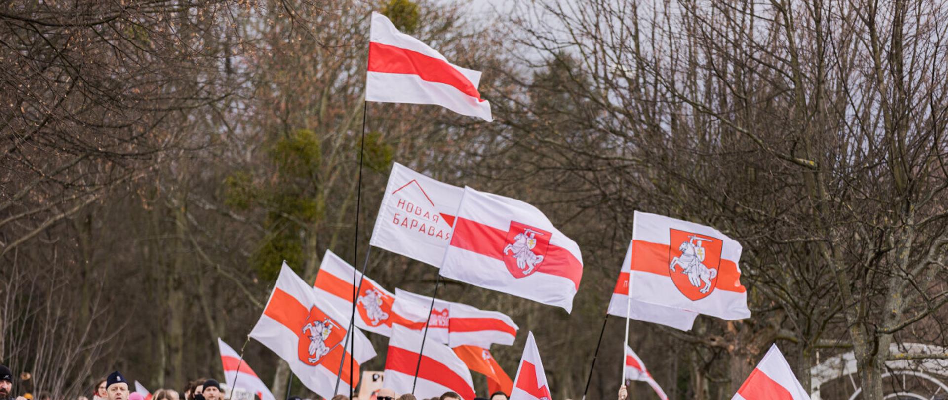 droga, na niej tłum ludzi niosących biało-czerwono-białe flagi 