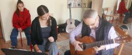 Prowadzący warsztaty gra na gitarze uczennicy.