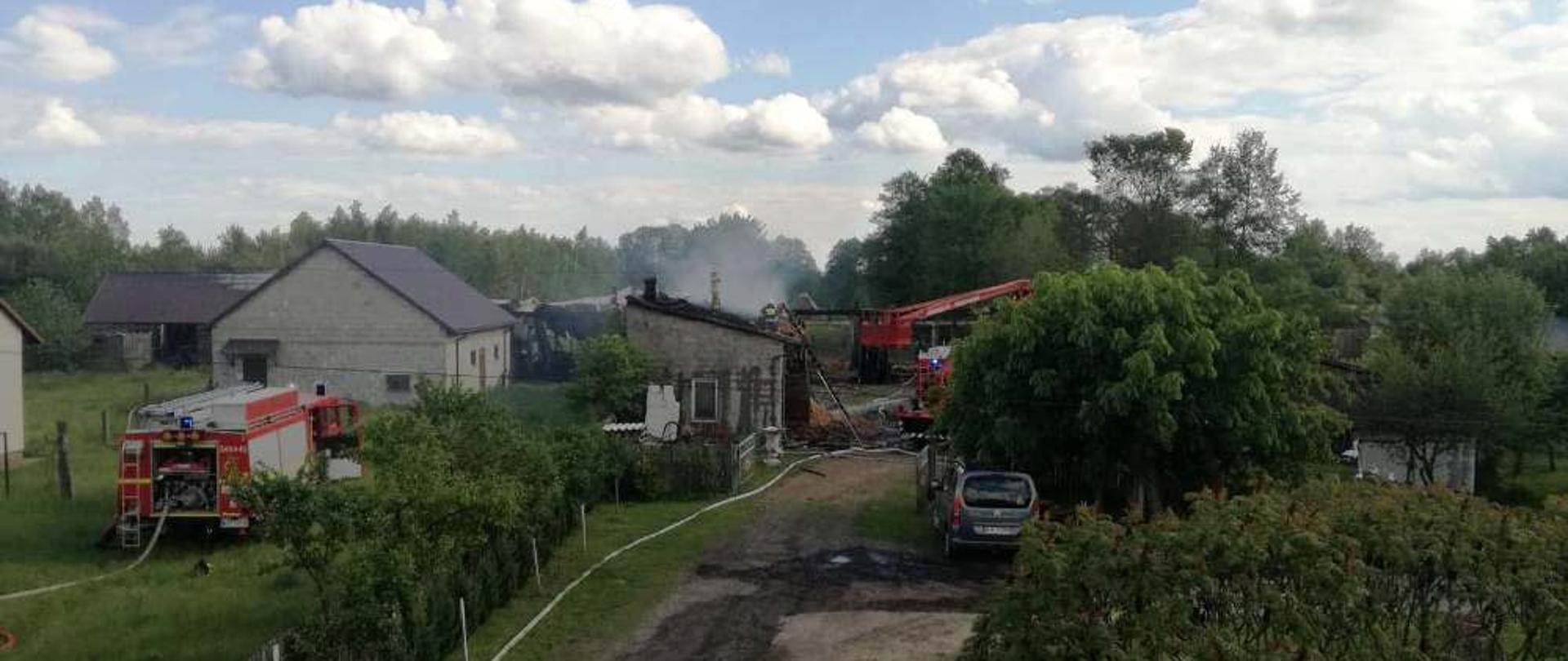 Pożar budynków gospodarczych w Klukowie. Na zdjęciu widoczne są zabudowania gospodarcze. Część obiektów objęta jest pożarem. Trwają działania gaśnicze, widać zastępy straży w rozwinięciu.