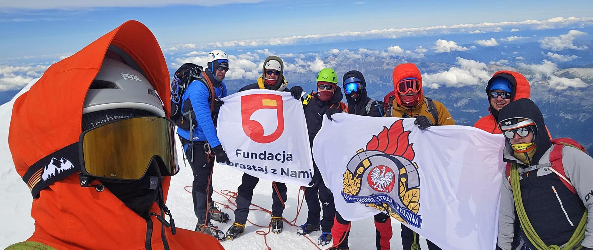 Strażacy na szczycie Mont Blanc trzymający flagi PSP oraz fundacji Dorastają z Nami