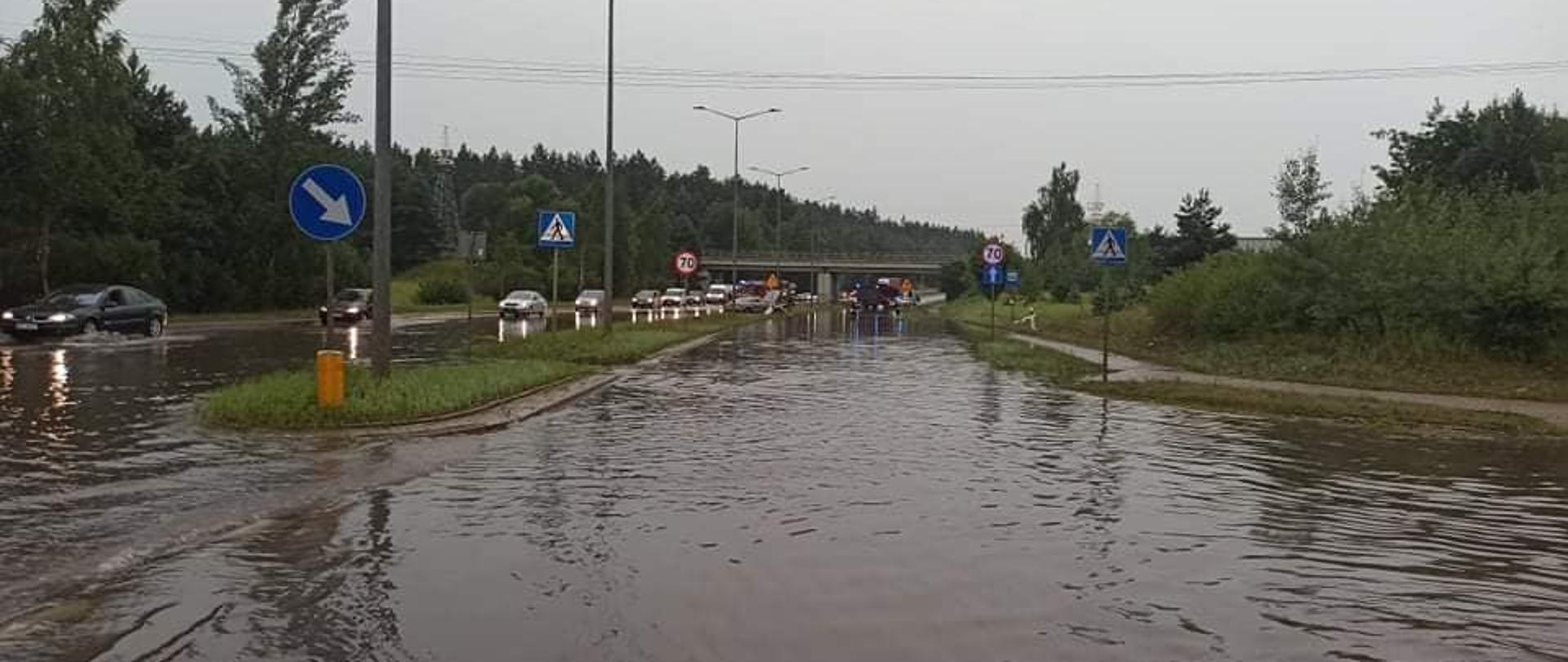 Zdjęcie przedstawia zalaną ulicę Przemysłową w Ełku na wysokości wiaduktu kolei wąskotorowej.