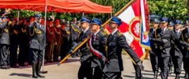 Na zdjęciu widać Uroczysty przemarsz pocztu sztandarowego Komendy Miejskiej PSP w Słupsku wraz za nim w marszu uczestniczą poddziały straży pożarnej.