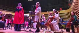 Prowadząca koncert oraz Orkiestra smyczkowa z Panią dyrygent na scenie sali koncertowej PSM