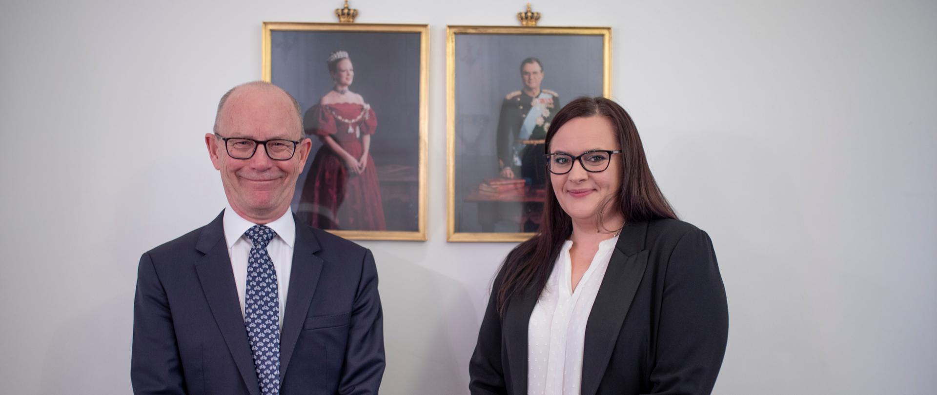 minister Małgorzata Jarosińska-Jedynak i ambasadorem Ole Egberg Mikkelsen stoją, za nimi na ścianie portrety duńskiej pary królewskiej