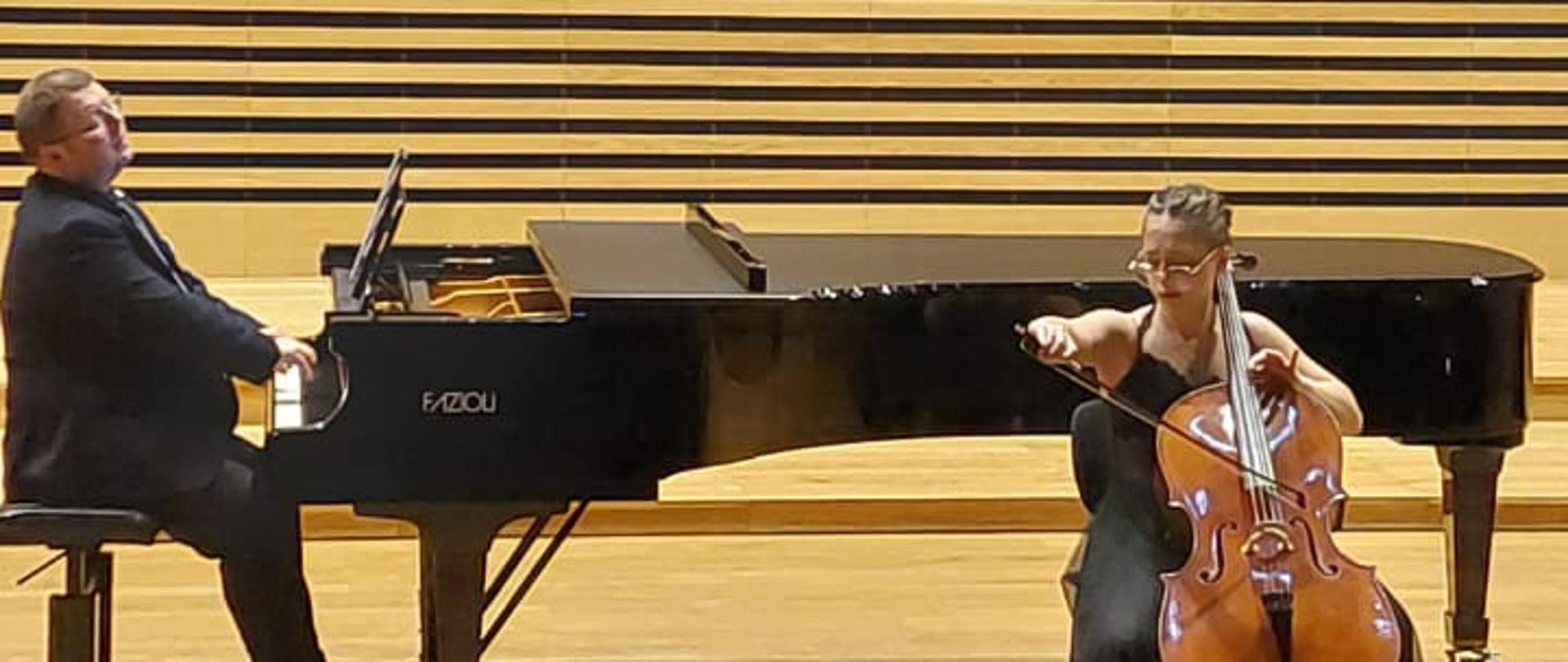 Dziewczyna gra na wiolonczeli, mężczyzna akompaniuje na fortepianie.