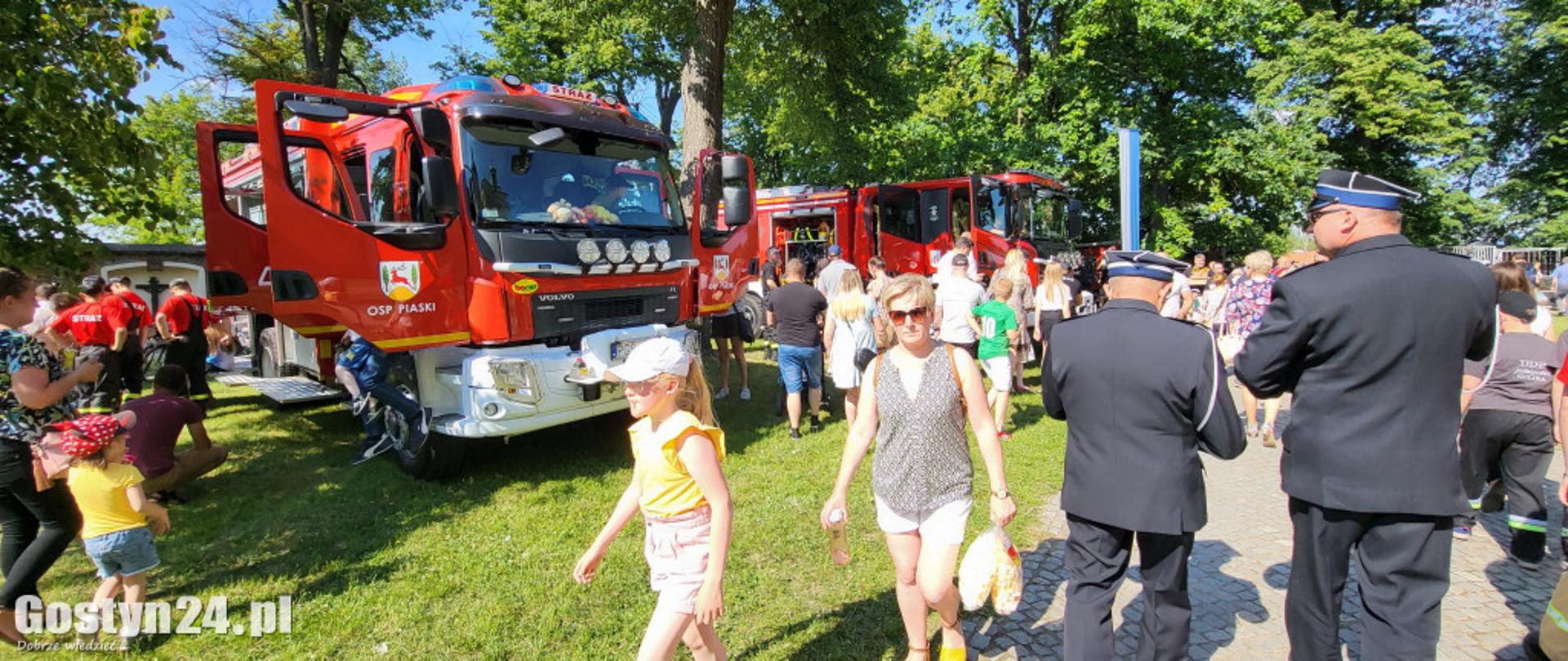Zdjęcie przedstawia ludzi oglądających pojazdy strażackie. 
