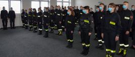Zdjęcie przedstawia grupę około czterdziestu strażaków uczestników kursu podstawowego. Strażacy stoją w pozycji na baczność ustawieni w czterech szeregach.