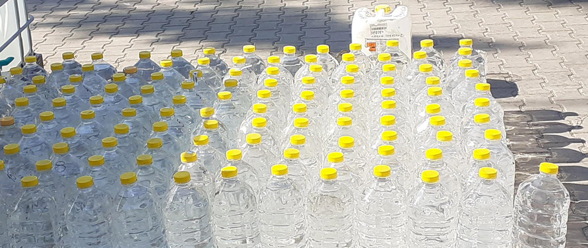 Ustawione na chodniku butelki plastikowe z przekazanym Straży Pożarnej alkoholem.