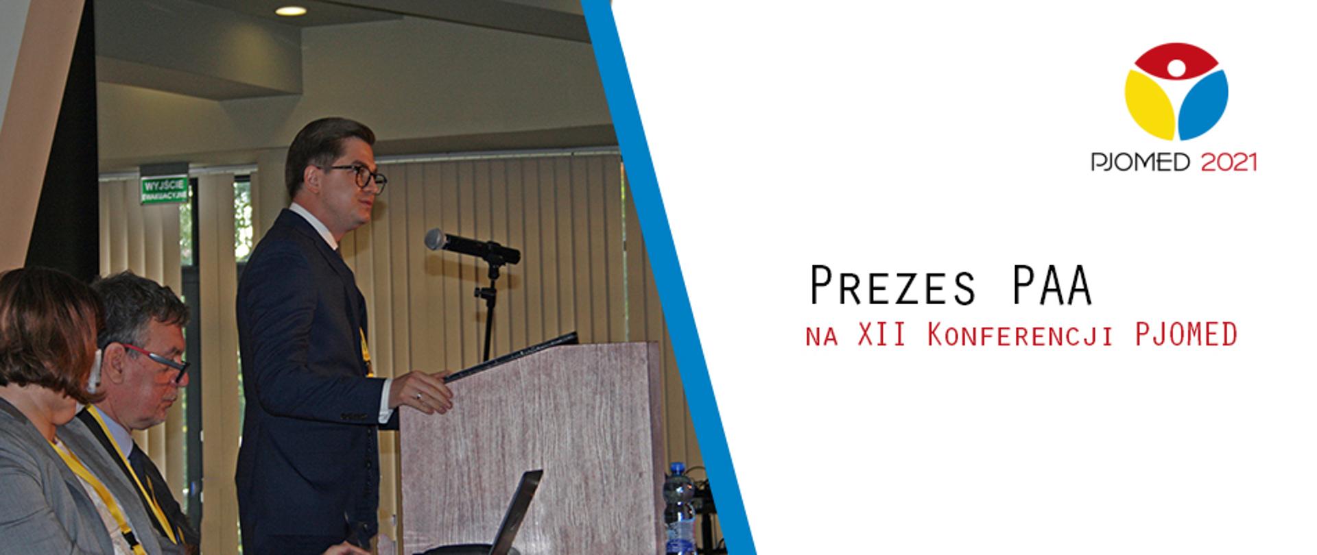 Dr Łukasz Młynarkiewicz, Prezes Państwowej Agencji Atomistyki na konferencji PJOMED 2021. Prezes stoi za mównicą z mikrofonem. Obok zdjęcia grafika - na białym tle czerwone i czarne napisy: "Prezes PAA na XII Konferencji PJOMED"