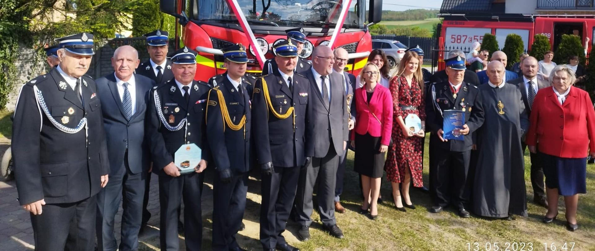 uczestnicy uroczystości strażacy druhowie politycy pozują do zdjęcia przed nowym samochodem pożarniczym