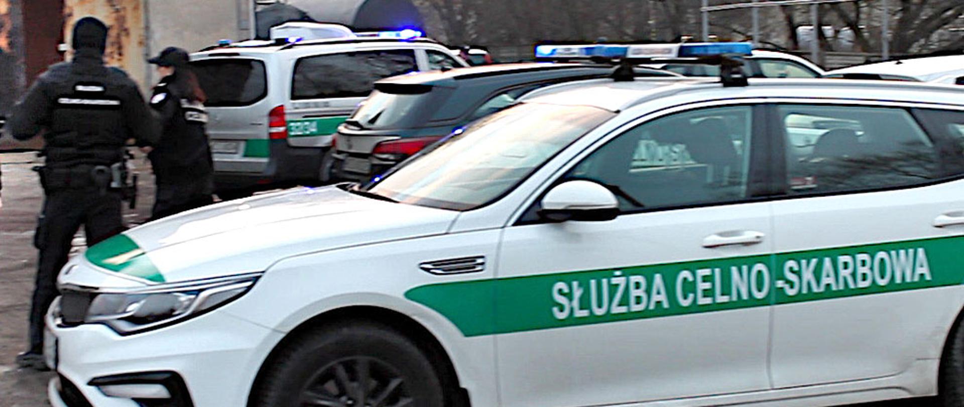 Samochód z napisem Służba Celno-Skarbowa i funkcjonariusze KAS.