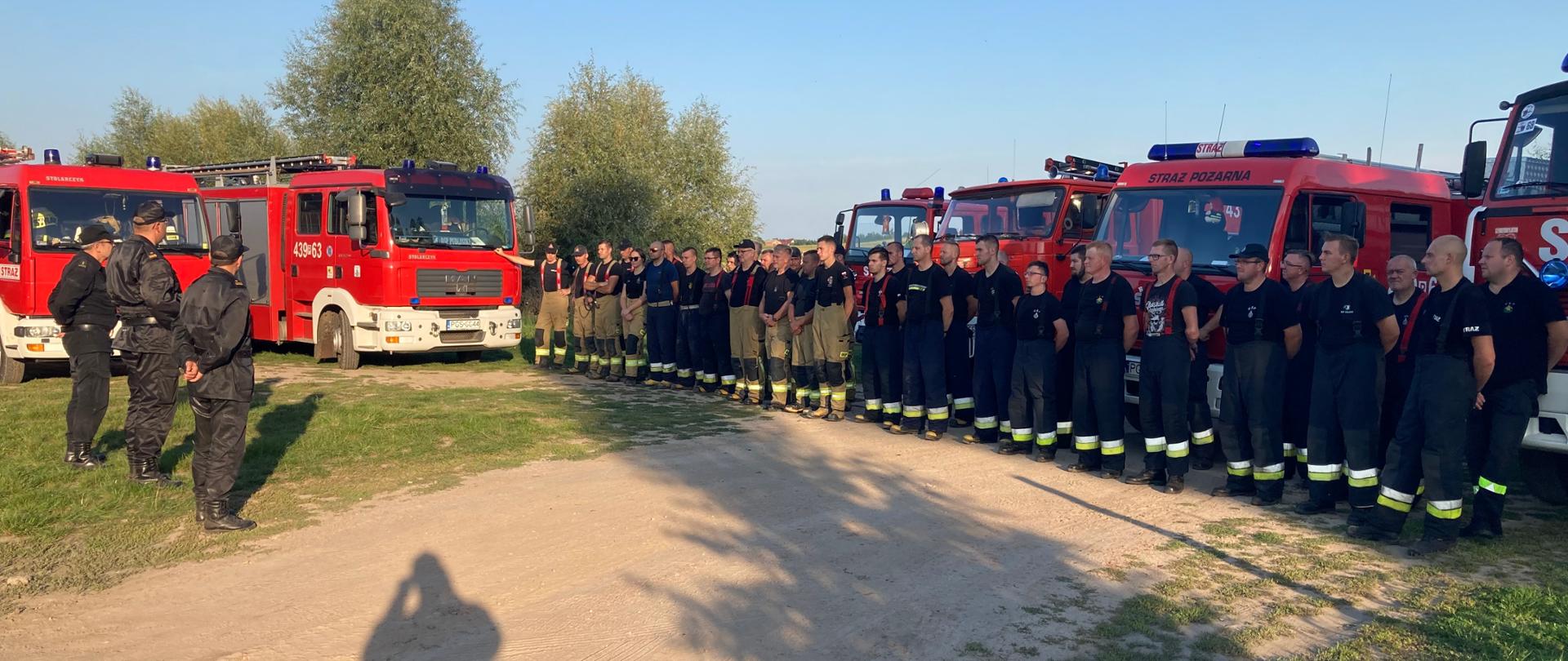 Zdjęcie przedstawia strażaków biorących udział w ćwiczeniach oraz kadrę kierowniczą komendy, która obserwowała przebieg ćwiczeń.