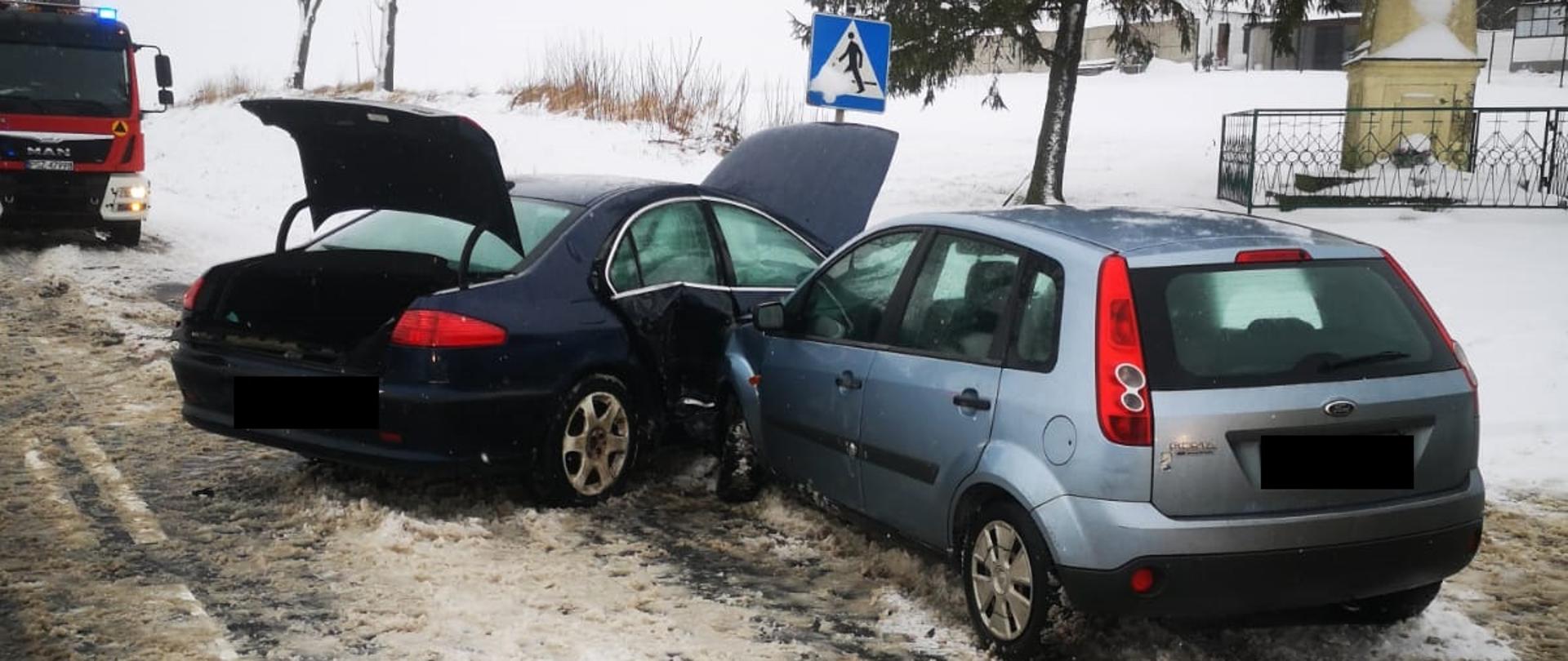 Widać dwa samochody, które zderzyły się ze sobą, znajdują się na drodze