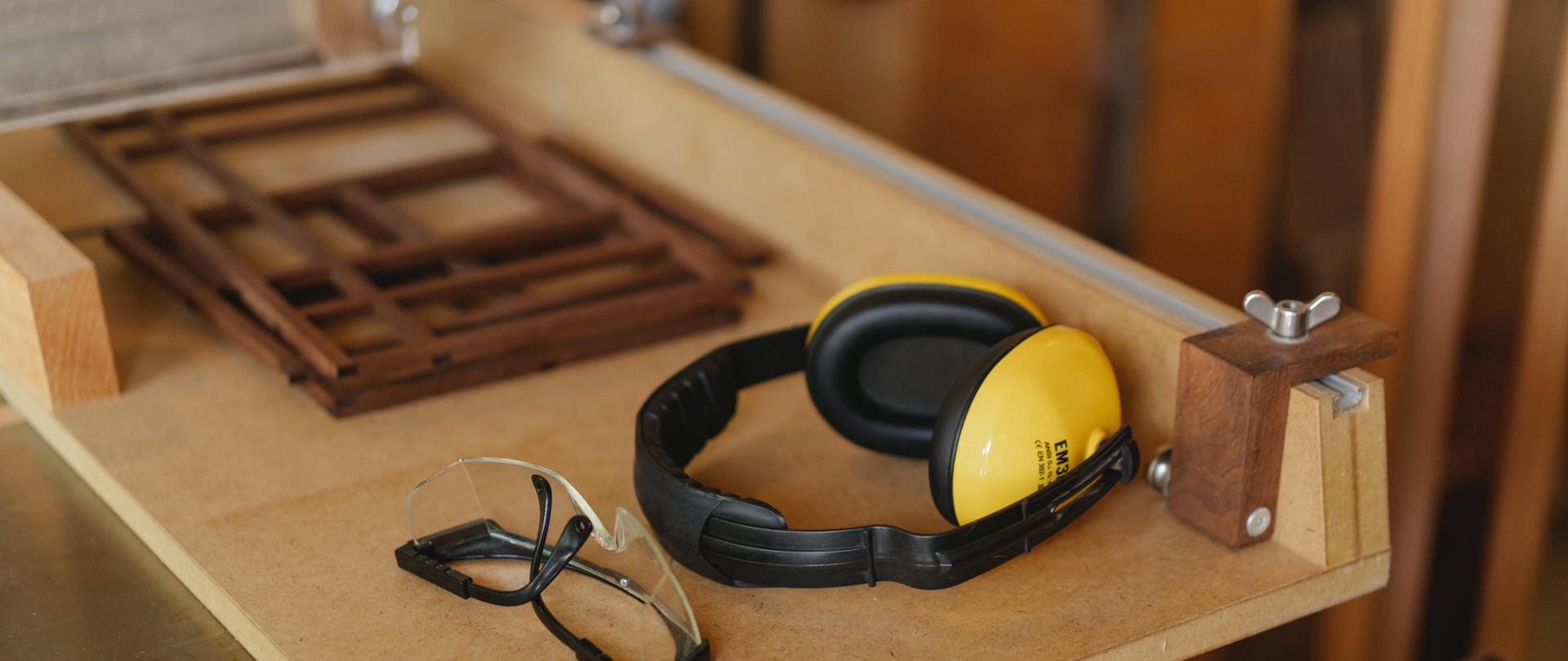 Na grafice możemy zobaczyć słuchawki chroniące przed hałasem oraz okulary ochronne.
