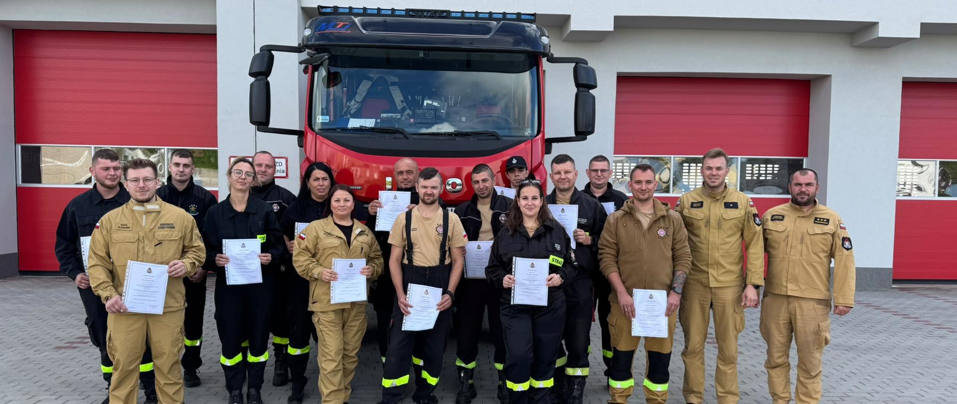 Zdjęcie przedstawia grupę strażaków z dyplomami ukończenia szkolenia dowódców OSP. W tle jednostka KP PSP Krosno Odrz. oraz samochód pożarniczy. 