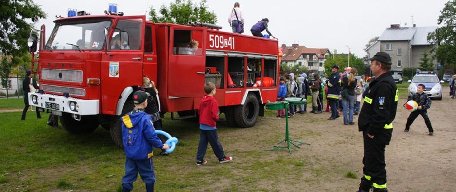 Zdjęcie przedstawia dzieci przy samochodzie pożarniczym