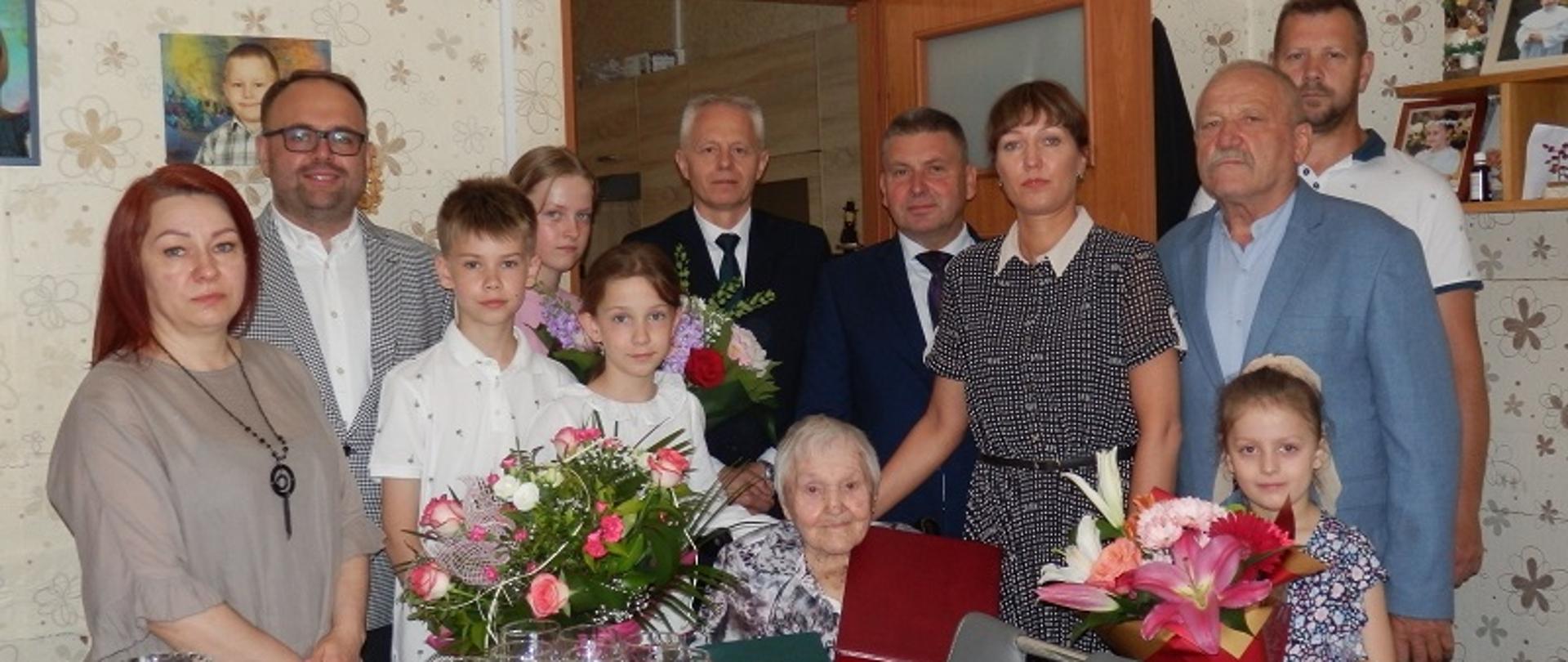 W centralnym miejscu Henryka Dąbrowska – Jubilatka, w otoczeniu członków rodziny, w tle Piotr Wszołczyk-Lipka Przewodniczący Rady Gminy, Jarosław Gago Kierownik Placówki Terenowej Kasy Rolniczego Ubezpieczenia Społecznego w Węgrowie, Zbigniew Kłusek Wójt Gminy Stoczek, Anna Paśnik Kierownik Urzędu Stanu Cywilnego, Mirosław Dąbrowski – syn Jubilatki. 