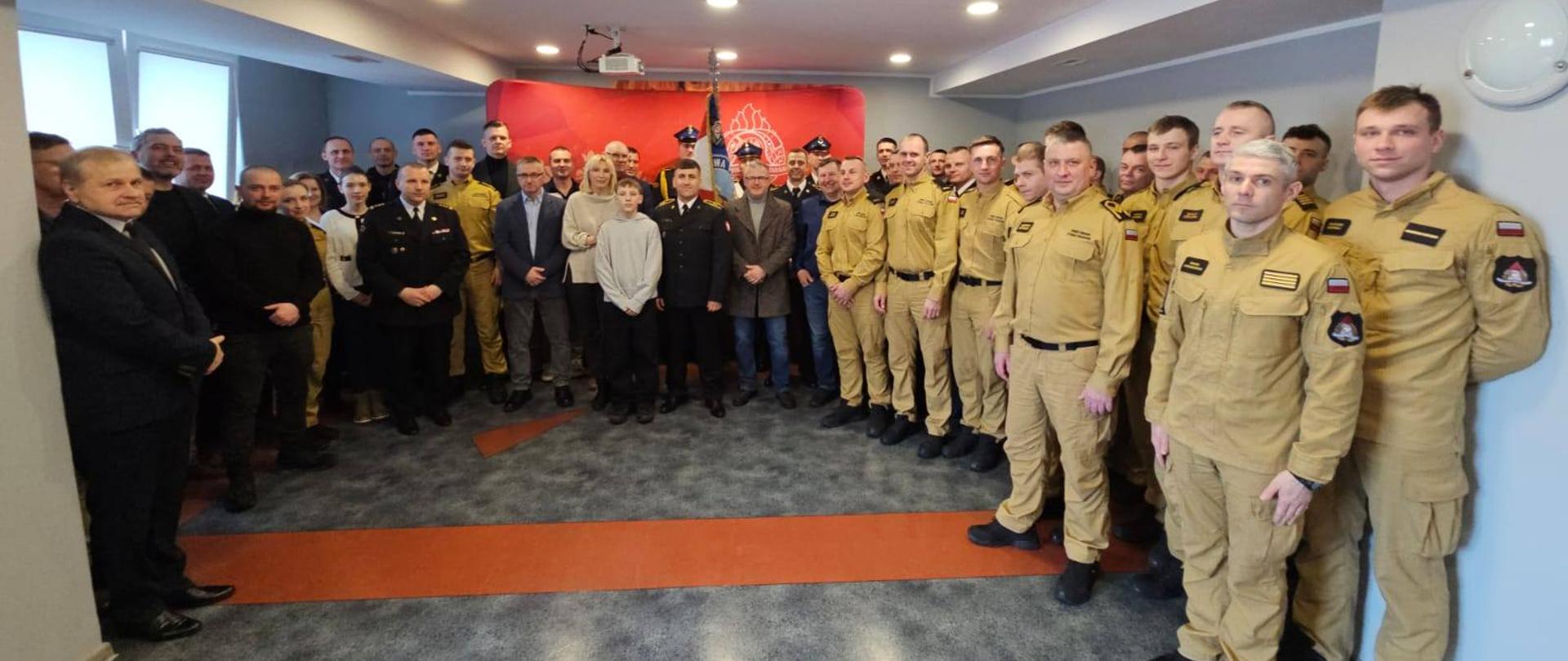 Świetlica. Na zdjęciu duża grupa strażaków oraz zaproszonych gości, pozują do zdjęcia.