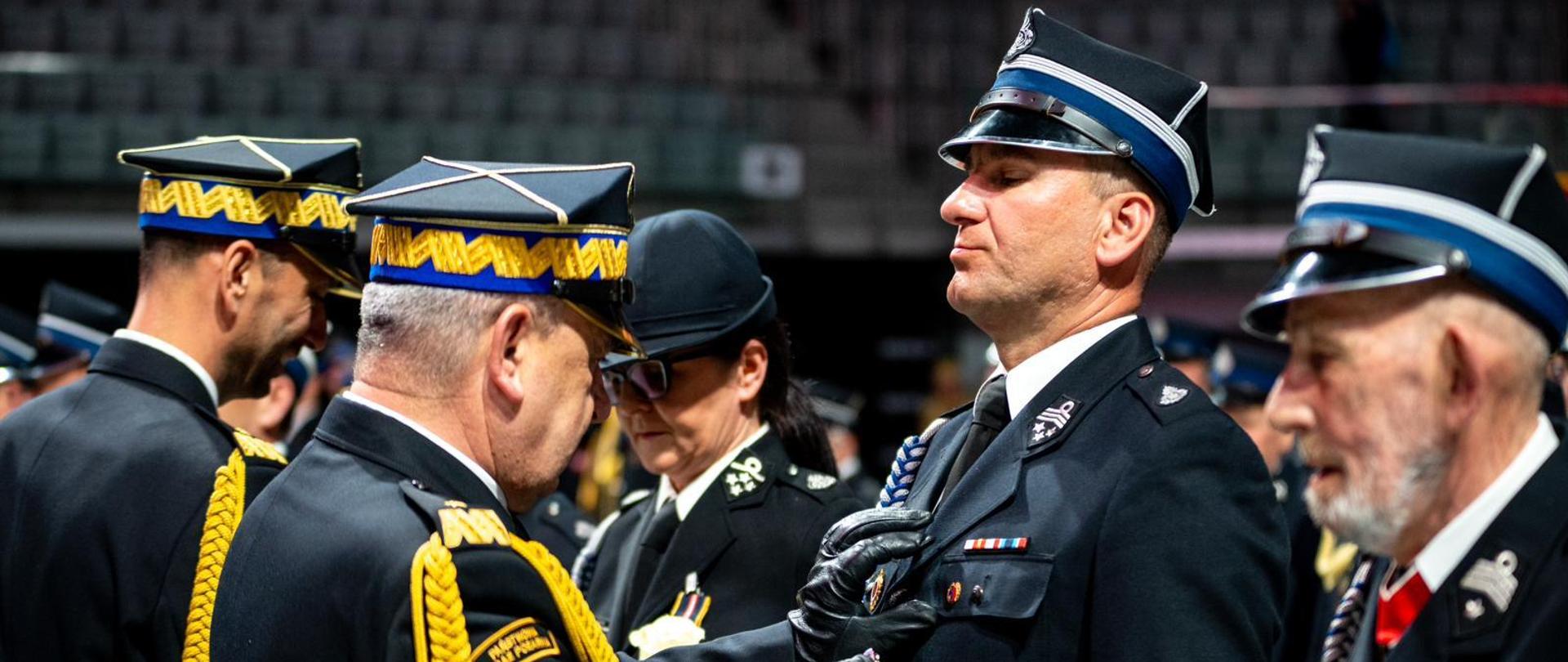 Zastępca komendanta głównego dekoruje druha OSP medalem.