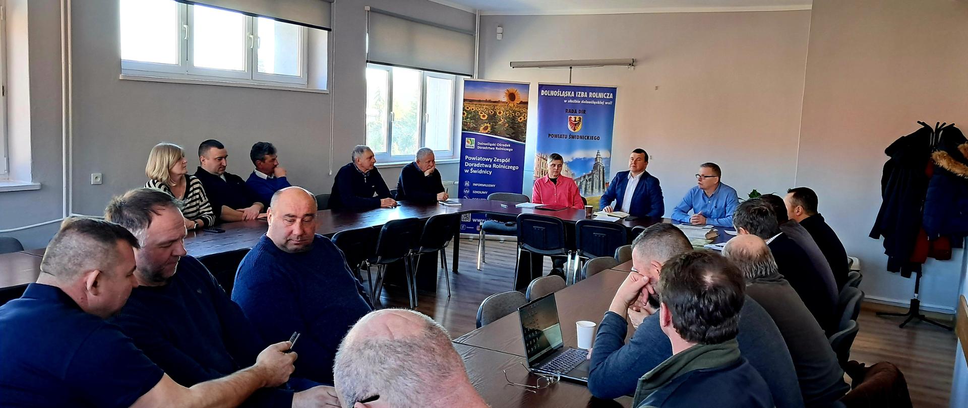 Siedzący przy stołach uczestnicy posiedzenia. W tle banery DIR i Powiatowego Zespołu Doradztwa Rolniczego w Świdnicy.