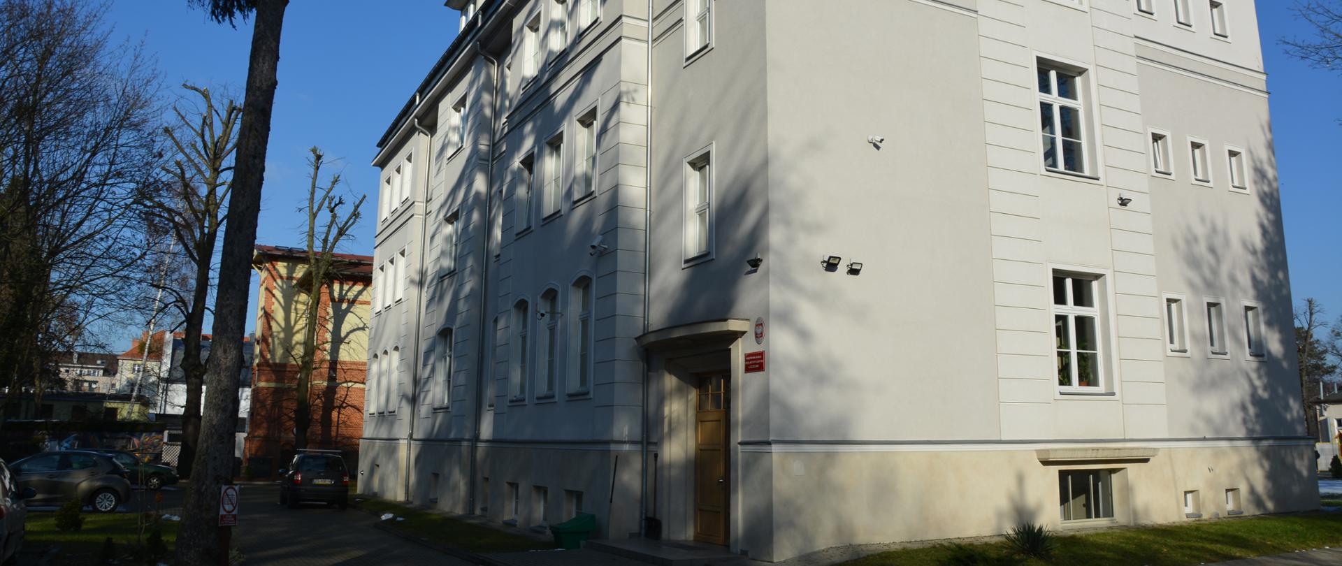 Budynek 3 piętrowy, jasna elewacja, widok od strony wejścia