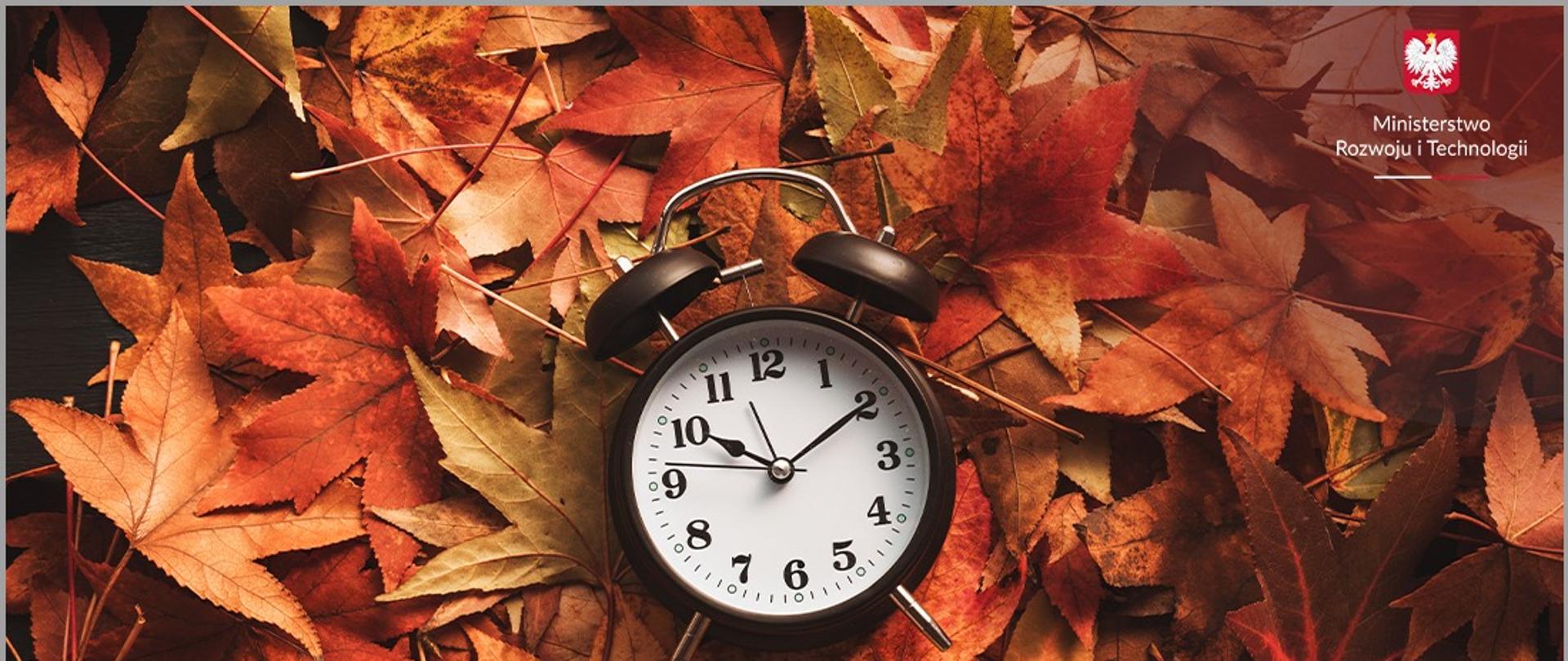 jesienne liście i leżący na nich zegar - symbolika zmiany czasu