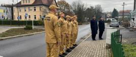 Strażacy PSP uczestniczą w ceremonii podniesienia flagi państwowej, ustawieni w szyku przed masztem. Uroczystość jest elementem obchodów o charakterze patriotycznym, podkreślającym szacunek dla symboli narodowych oraz tradycji służby pożarniczej.