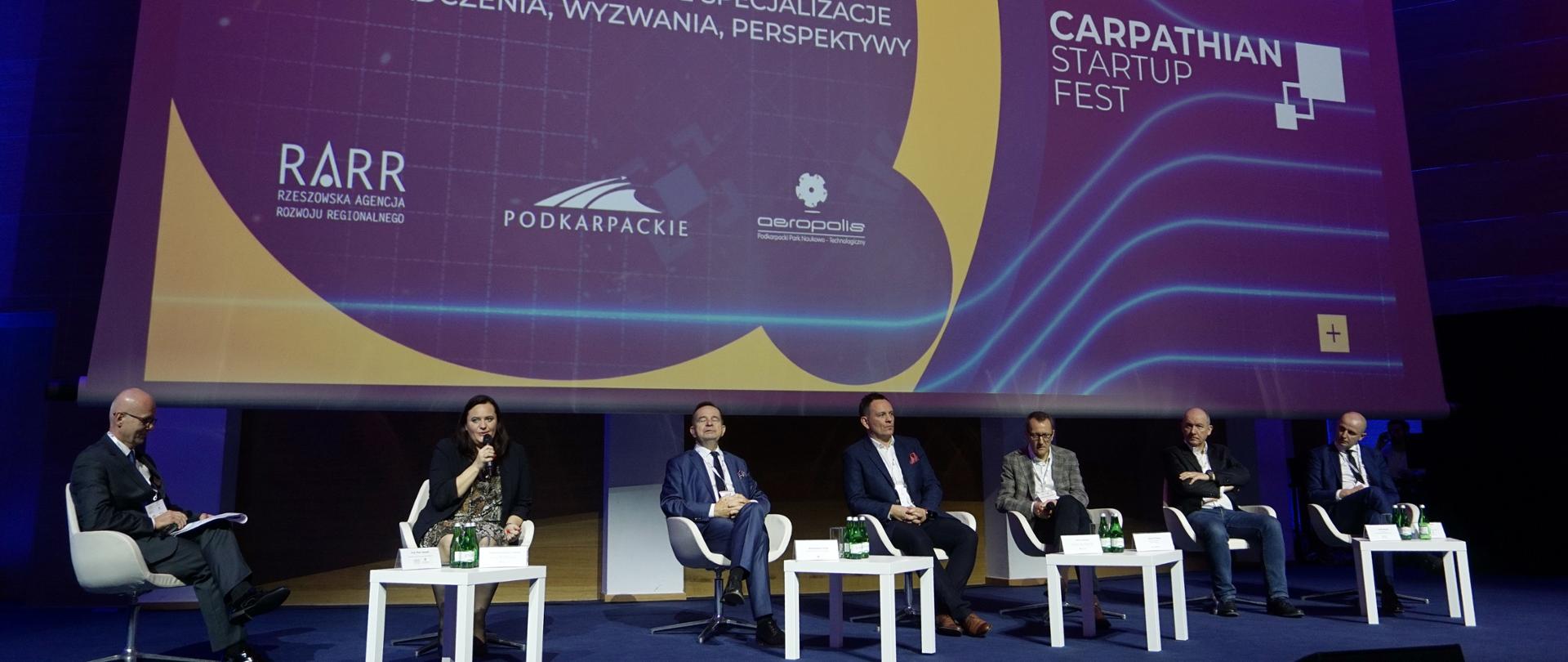 Grupa osób siedzi na scenie podczas panelu wśród nich minister Jarosińska-Jedynak