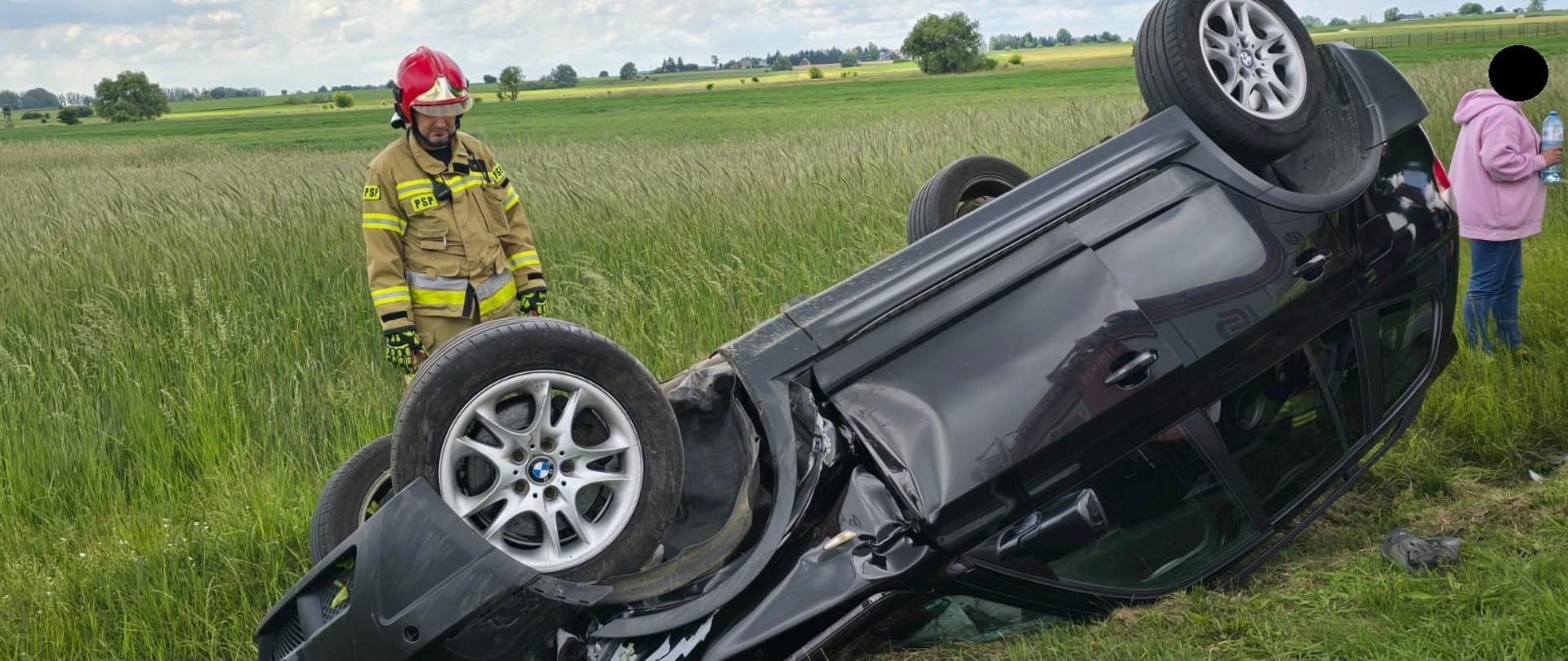Samochód po dachowaniu w rowie, w pobliżu strażak