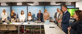 Kilka osób stoi nad stołami konferencyjnymi