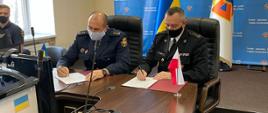 Dwóch strażaków podpisujący umowę o współpracy 
