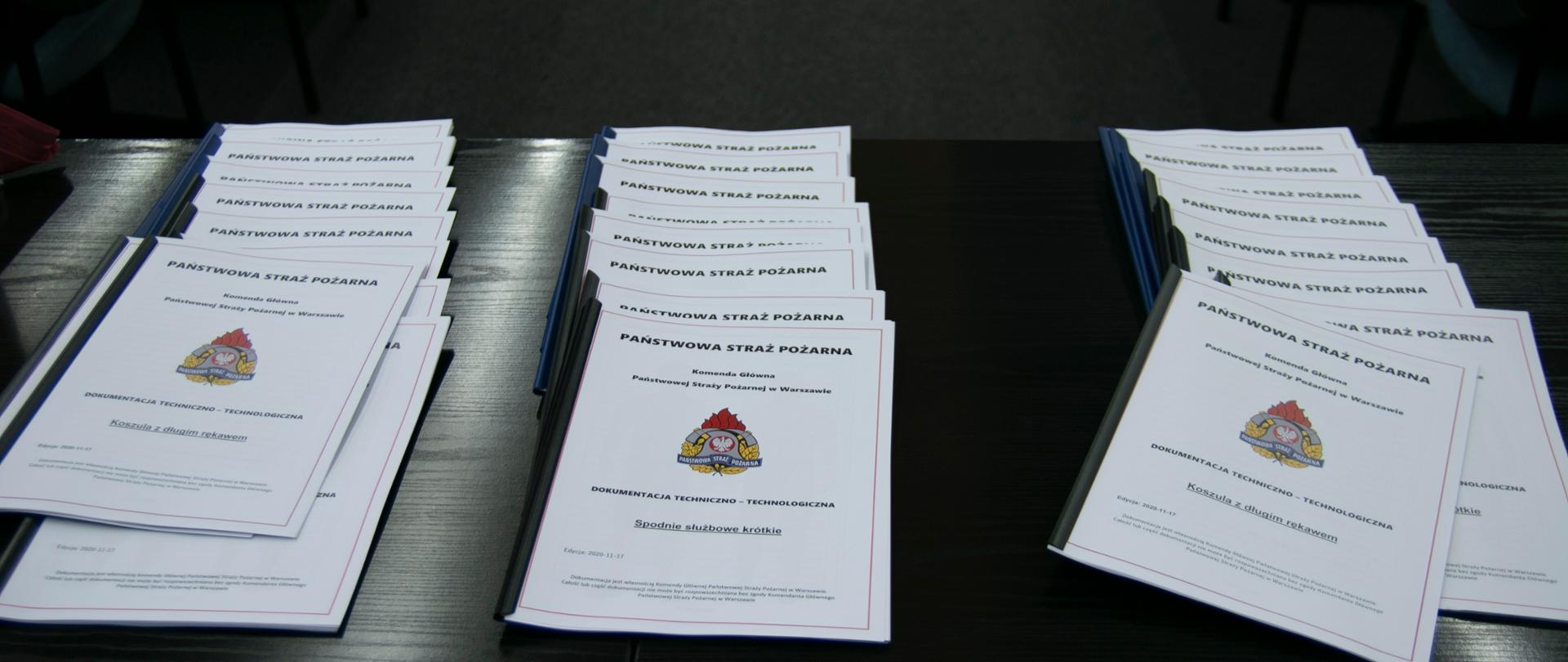 na stole zaprezentowana jest dokumentacja do nowego umundurowania dla funkcjonariuszy PSP
