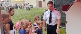 Na zdjęciu funkcjonariusz straży pożarnej prezentuje mobilny symulator zagrożeń pożarowych na dożynkach 