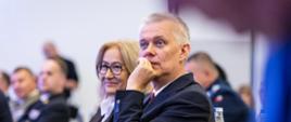 Zdjęcie przedstawia siedzącego na konferencji InSec 2026 ministra Tomasza Siemoniaka. Po lewej stronie, obok ministra, siedzi Maria Małgorzata Janyska, przewodnicząca Sejmowej Komisji Administracji i Spraw Wewnętrznych. Za ministrem widać butelki z wodą i szklankę. W tle inni uczestnicy konferencji.