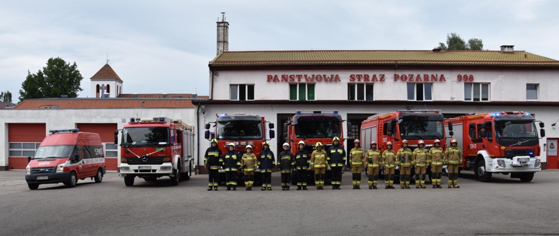Strażacy stoją na zbiórce i przy dźwiękach alarmowych samochodów strażackich, oddają hołd poległym w Powstaniu Warszawskim. 
