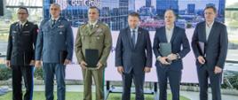 Na zdjęciu przedstawiciele służb mundurowych w ubraniach wyjściowych, trzymający w teczkach podpisane porozumienia oraz Minister Spraw Wewnętrznych i Administracji