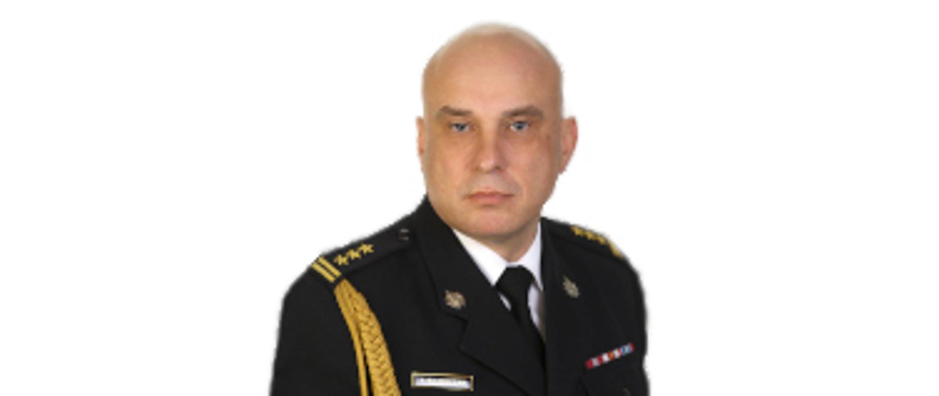 Na obrazie znajduje się portret starszego brygadiera Tomasza Bajerczaka, Komendanta Miejskiego Państwowej Straży Pożarnej w Zabrzu. Mężczyzna jest łysy, ma jasną karnację i niebieskie oczy. Ubrany jest w wyjściowy mundur PSP, na którym widoczne są: z prawej strony (patrząc na zdjęcie): baretki z odznaczeniami. Z lewej strony (patrząc na zdjęcie): imiennik z napisem "T. BAJERCZAK". Na pagonach: dystynkcje w postaci trzech złotych gwiazdek i dwóch pasków, co odpowiada stopniowi starszego brygadiera. Na jego prawym rękawie: złoty sznur oficerski. Mundur uzupełnia biała koszula i ciemny krawat. Tło obrazu jest jednolicie białe. Mężczyzna patrzy prosto przed siebie z poważnym wyrazem twarzy.