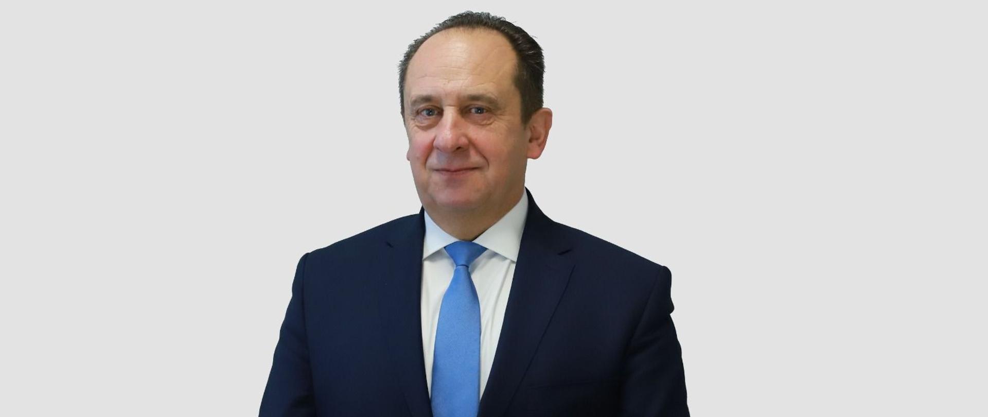 Andrzej Gut-Mostowy stojący na białym tle