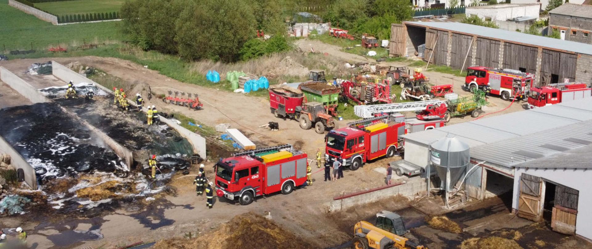 Zdjęcie z lotu ptaka, które przedstawia zastępy pożarnicze stojące na terenie gospodarstwa. 