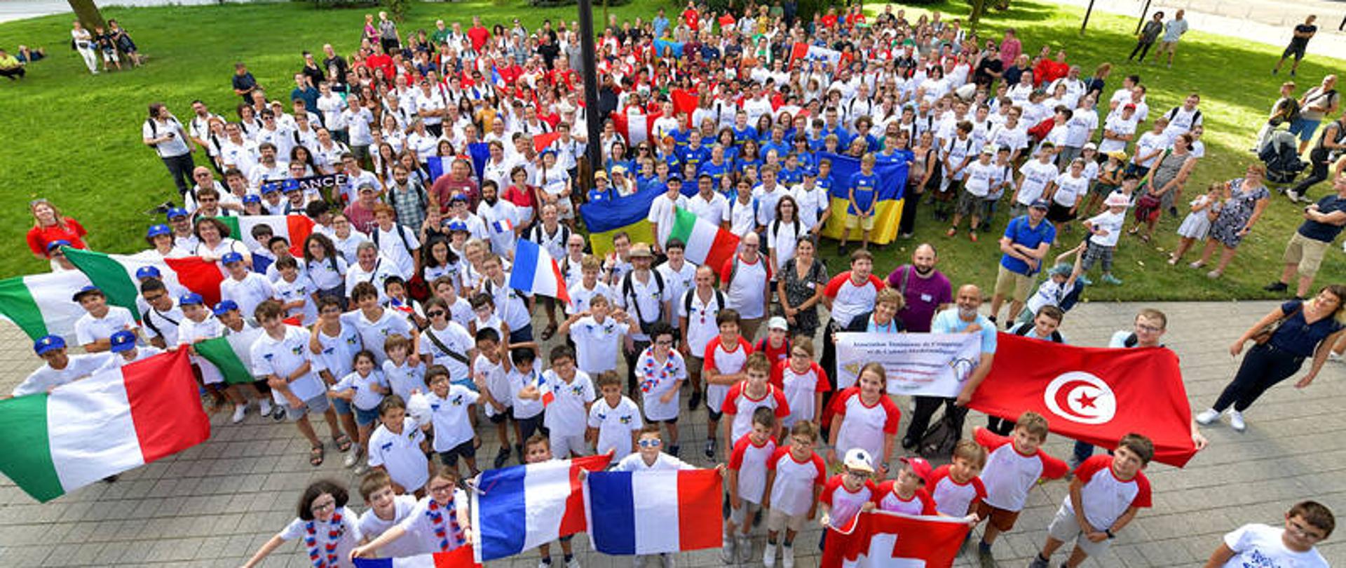 Fotografia z góry. Na dole duża grupa młodzieży z flagami swoich krajów.