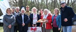 Grupa ludzi stoi na podwórku w słońcu, uśmiechają się i pozują do zdjęcia 