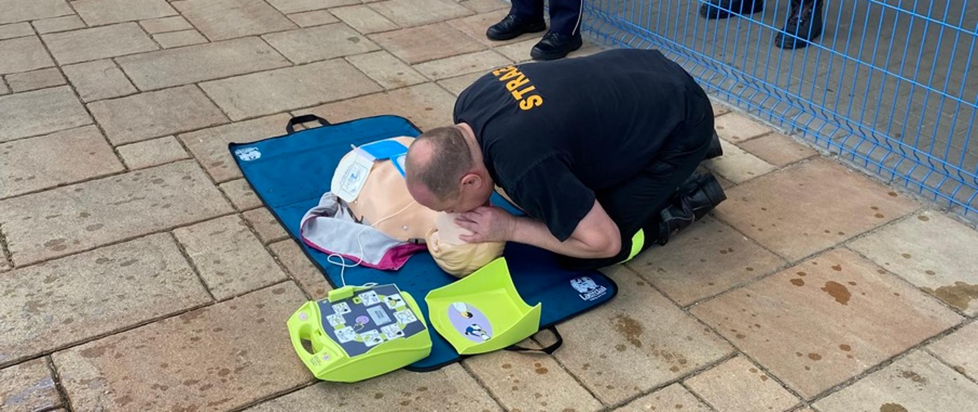 Ratownicy PSP podejmują poszkodowanego na basenie.