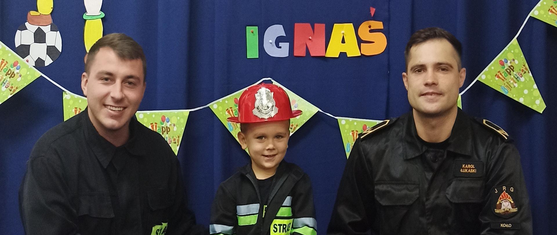 Na zdjęciu widać funkcjonariuszy KP PSP KOŁO z dzieckiem przebranym za strażaka, który tego dnia obchodził urodziny