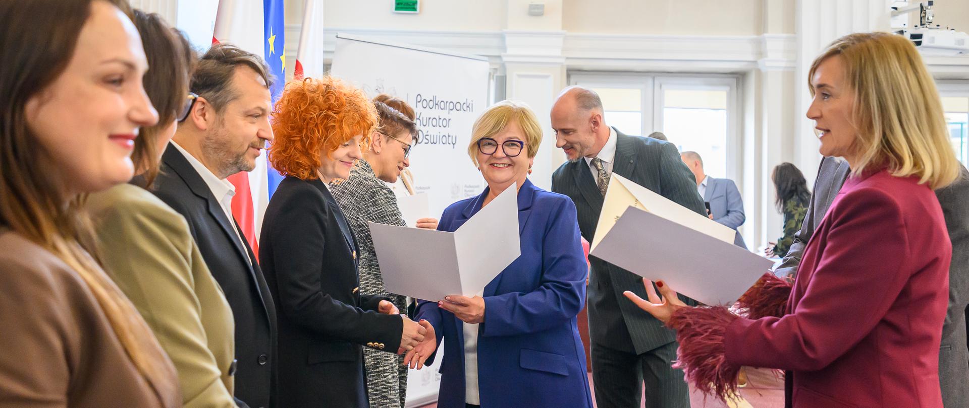 Zdjęcie przedstawia wojewodę podkarpackiego Teresę Kubas-Hul, podkarpackiego kuratora oświaty Dorotę Nowak-Maluchnik i podkarpackich nauczycieli podczas uroczystości wręczenia nagród z okazji Dnia Komisji Edukacji Narodowej