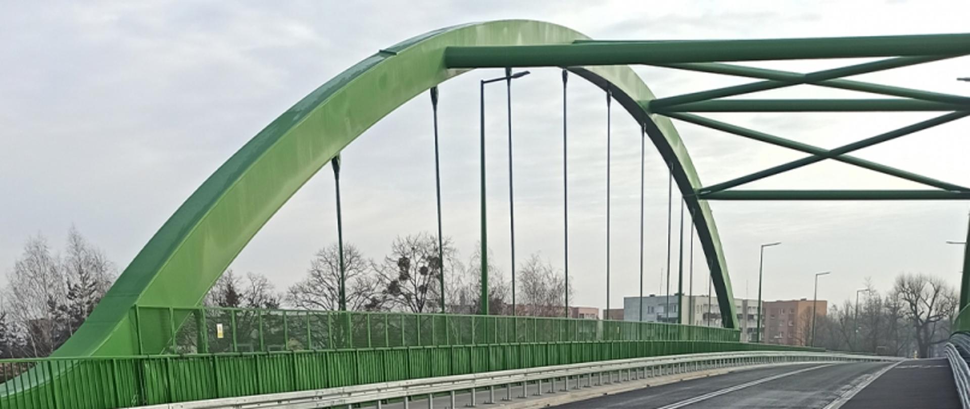 Zielony wiadukt z poziomu ulicy. Ulica jest pusta.
