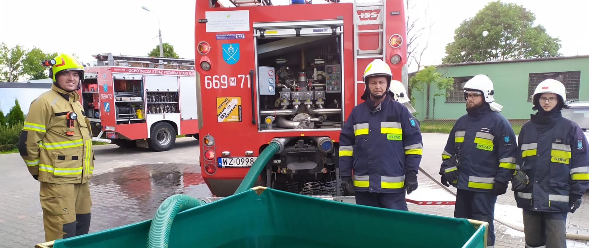 Strażacy podczas egzaminu przy zbiorniku wodnym sprawiający linię ssawną